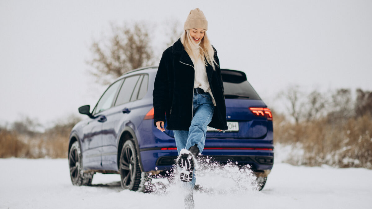 Femme en vêtements d'hiver à côté de sa voiture