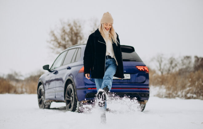 Femme en vêtements d'hiver à côté de sa voiture